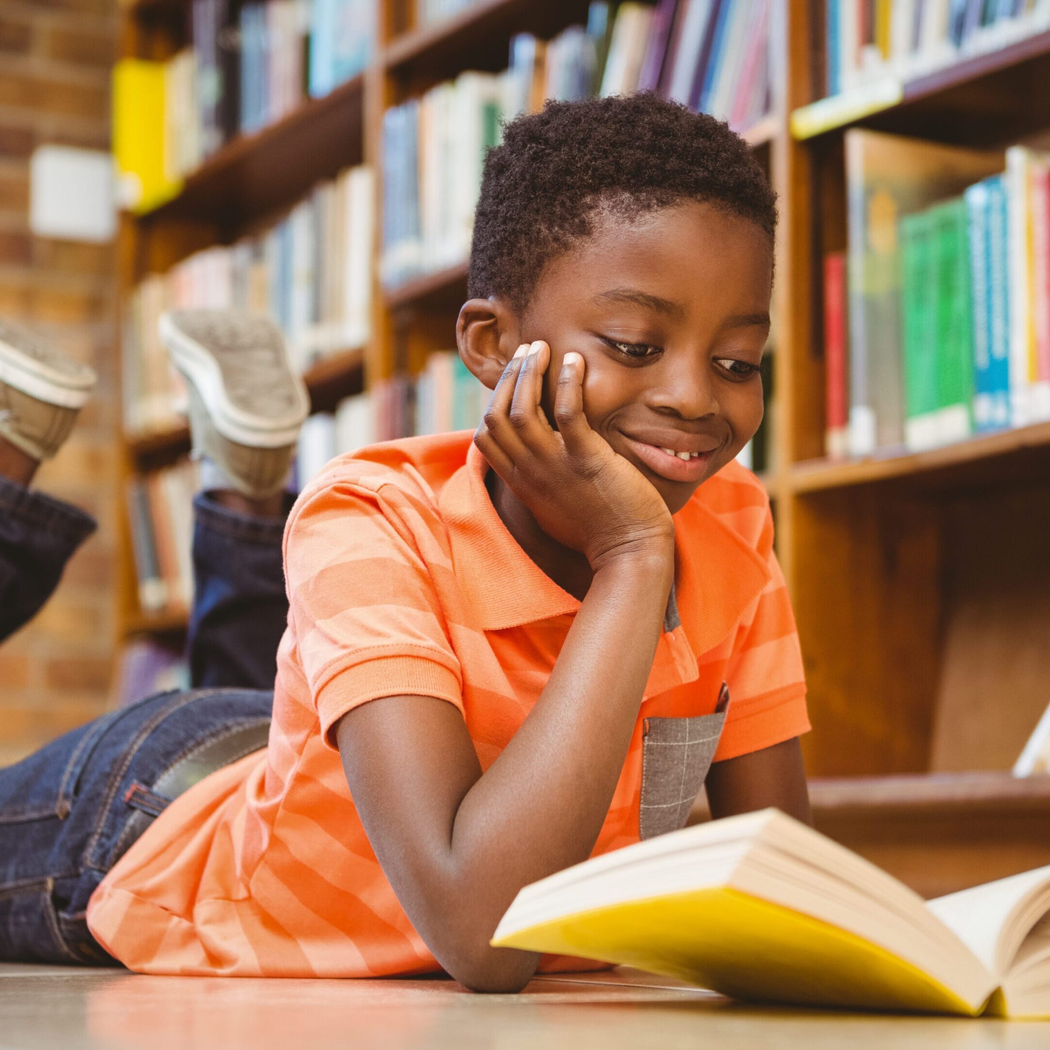 Child reading book in library, smiling.